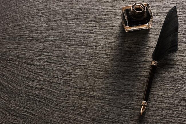 Feather pen and inkwell over slate